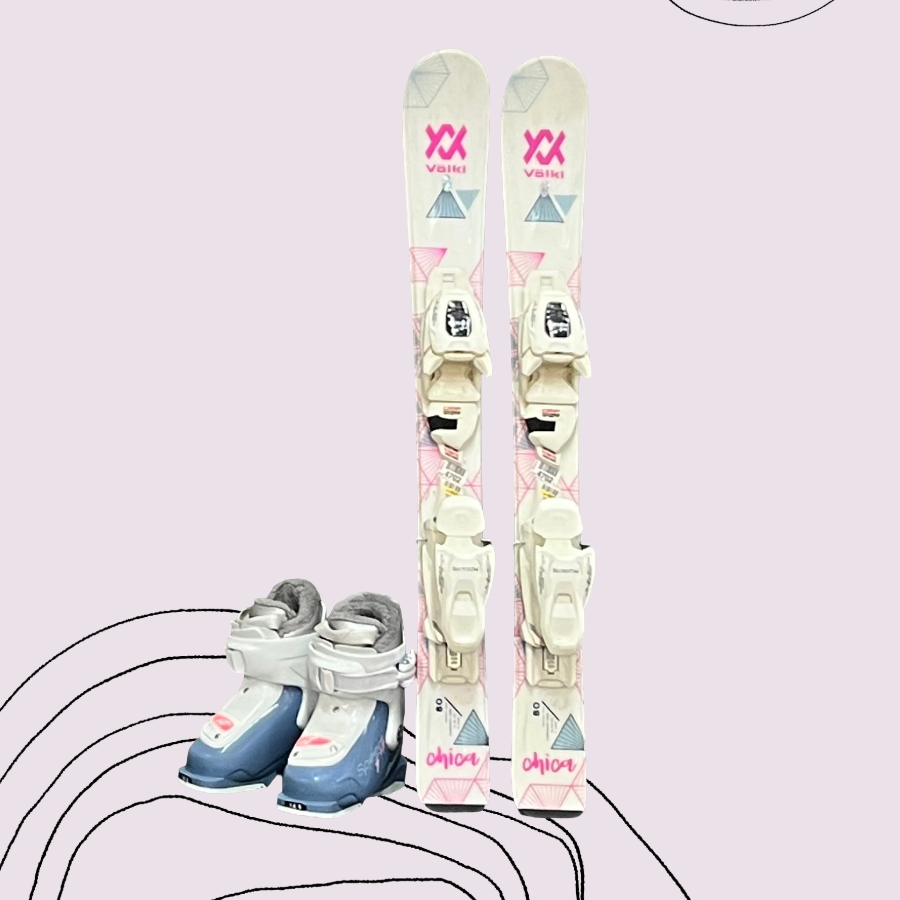 Pair of Toddler -sized pink & white Volkl skis with white bindings and a white & blue Nordica ski boot on a light pink background