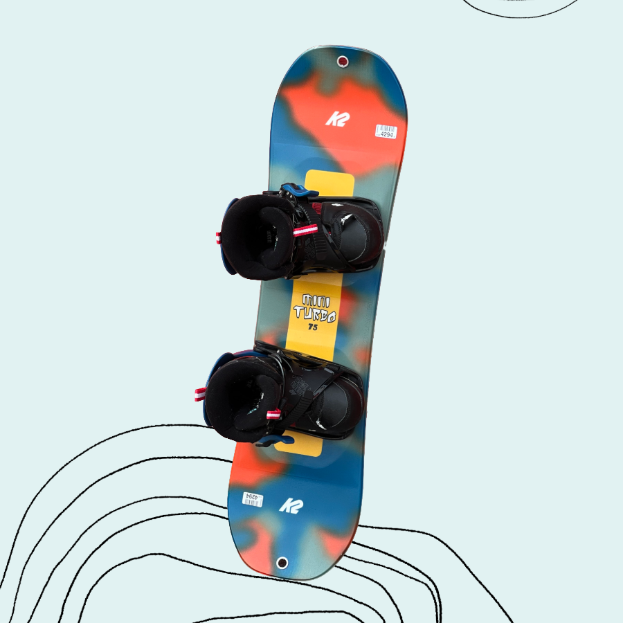 A toddler-sized colorful K2 snowboard with black bindings on a light blue background
