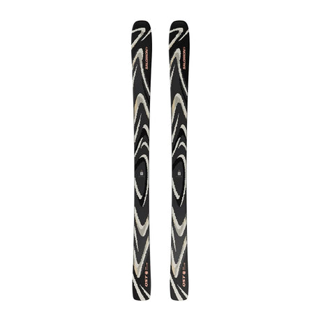 A pair of skis with a black base featuring a swirling zebra-like pattern in beige and white, with small red and orange logo details near the tips.