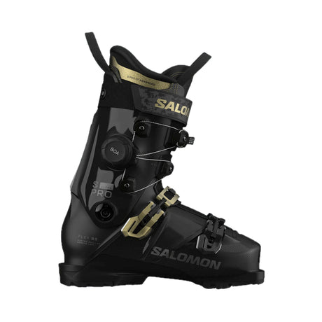 A Salomon ski boot in black with gold accents, featuring a dial closure system and a quick-release buckle, shown from a side profile on a white background.
