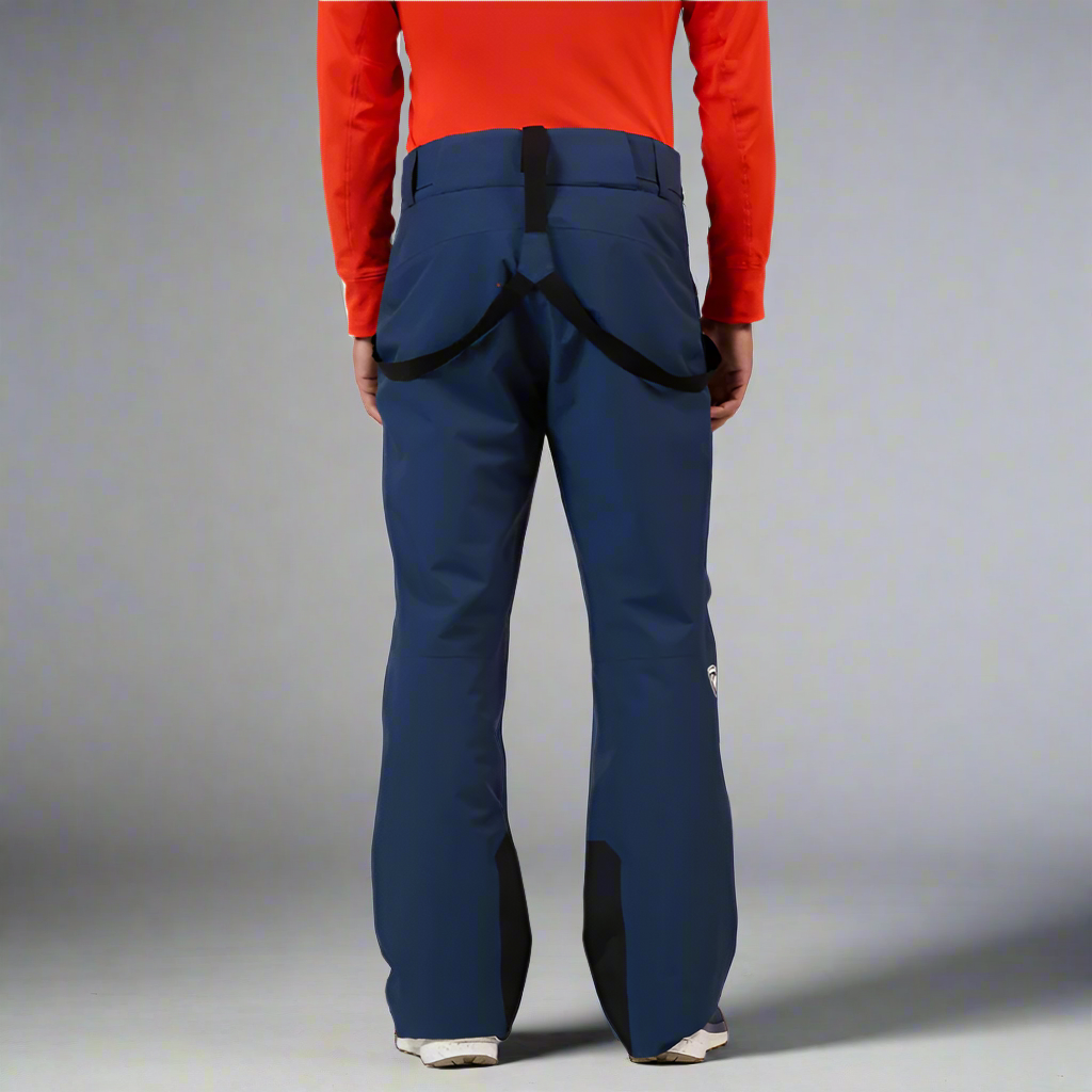 Person wearing blue snow pants with a red top on a white background