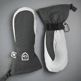 Pair of grey and white mittens with a visible Hestra logo on a grey background